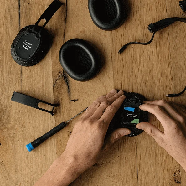 Hands assembling a modular Fairphone headphone, showcasing the sustainable and repairable design.